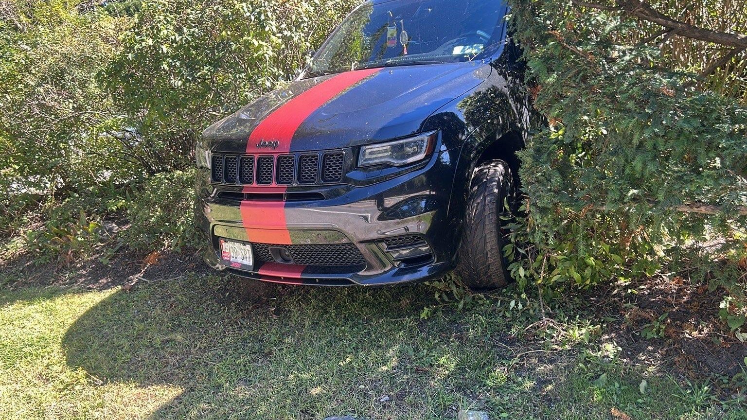 Black Jeep stuck in landscaping after leaving the road